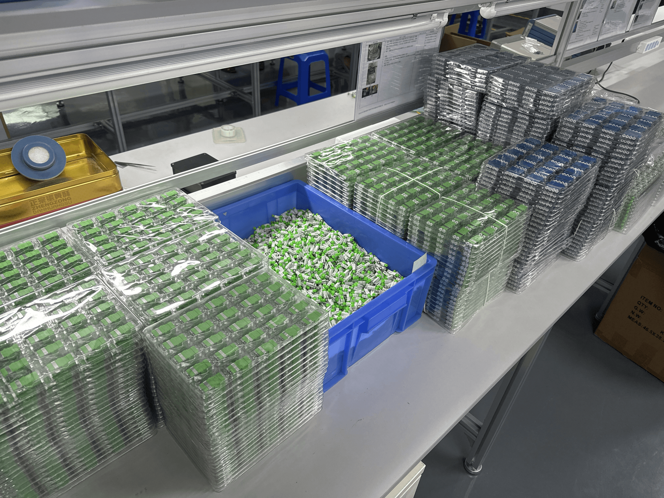 Batches of fiber optic adapters organized at the assembly bench
