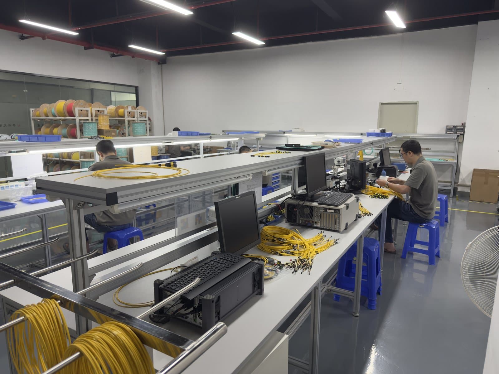 Fiber optic assembly workshop with operators at production benches