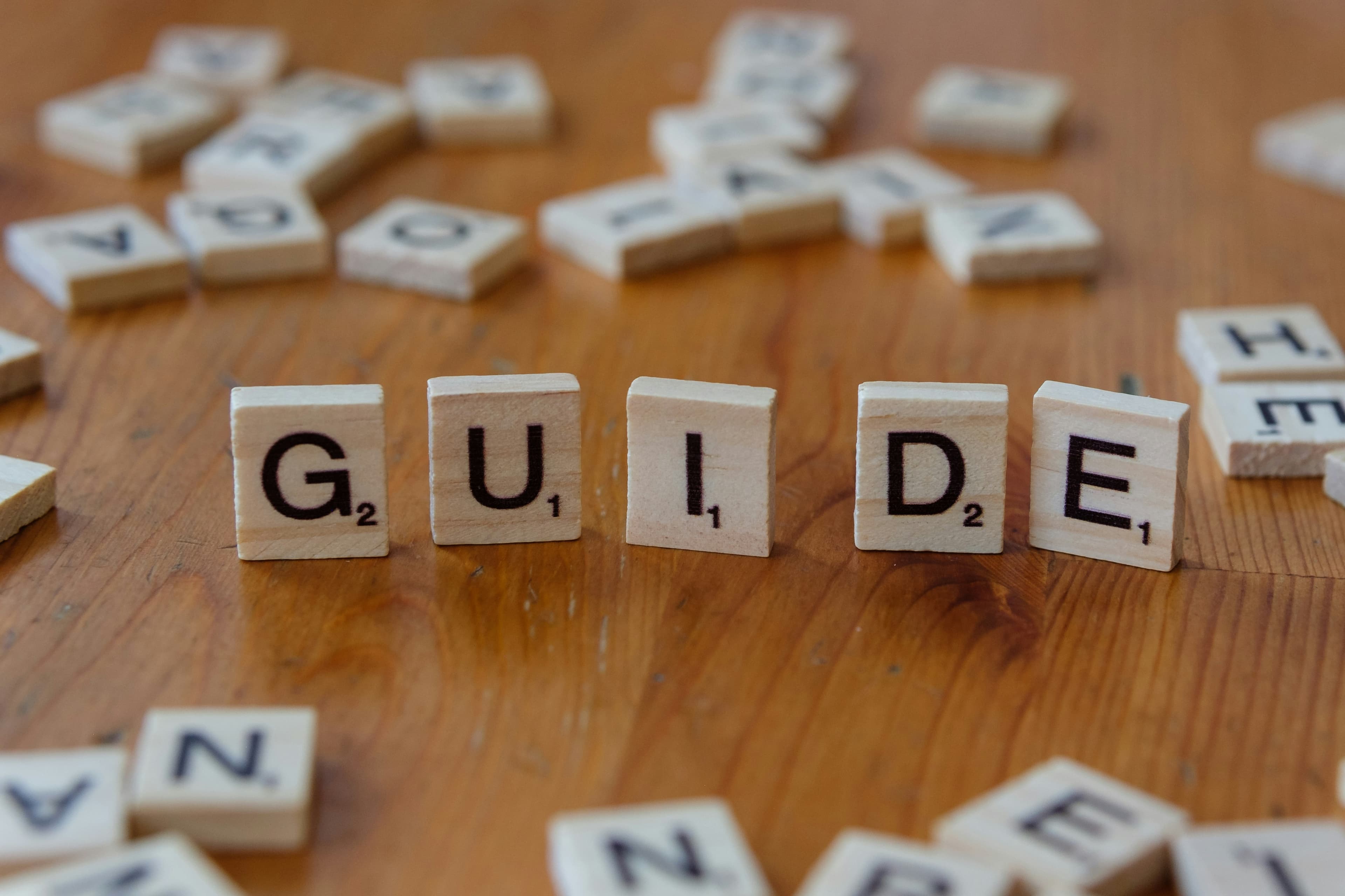 Wooden letter tiles spelling Guide on a table